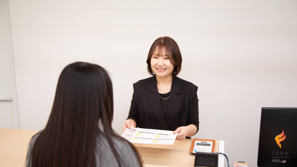 笑顔でお会計をする美容室フェイスのスタッフ